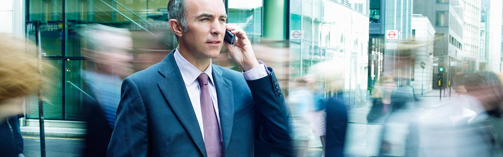 Business man on phone in middle of busy street.